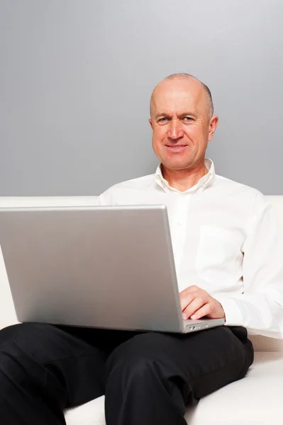 Foto van smiley senior man met laptop — Stockfoto