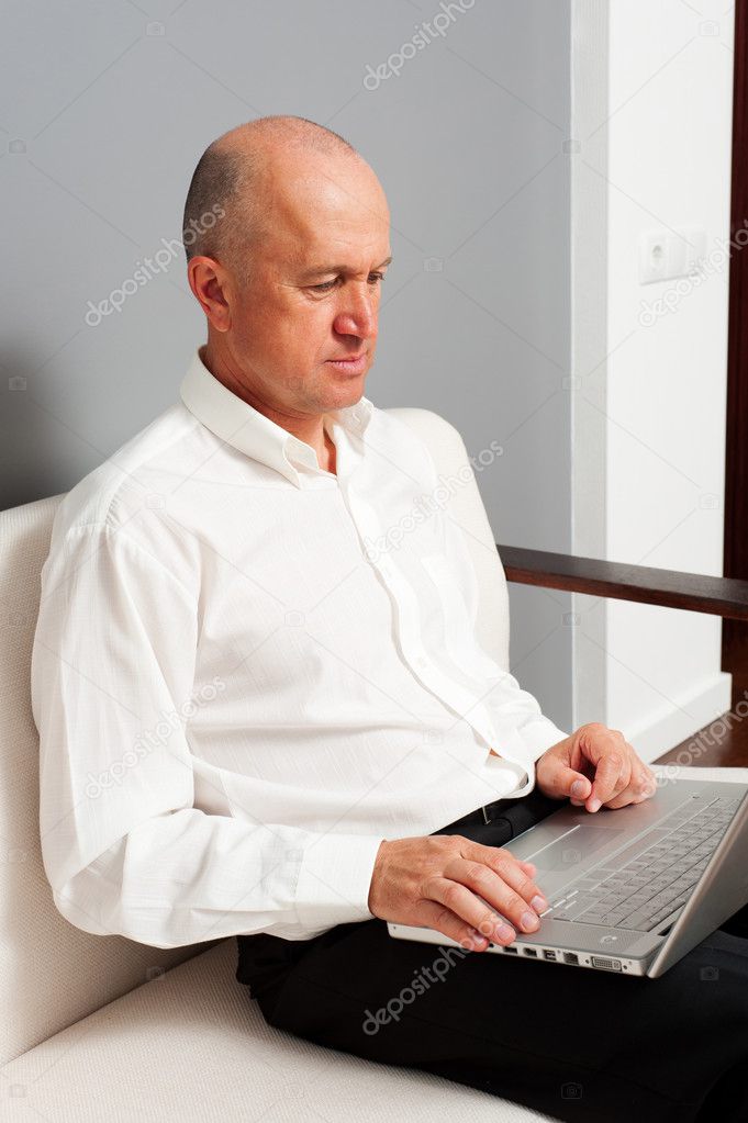 Photo of serious senior man with laptop