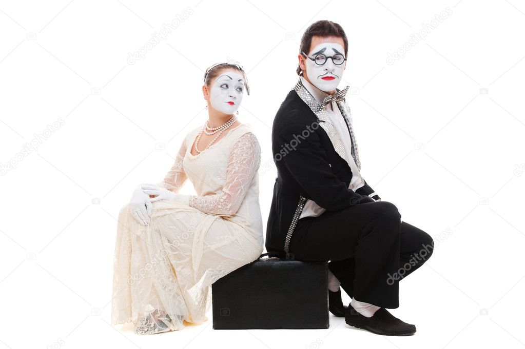 Studio shot of two mimes sitting on suitcase