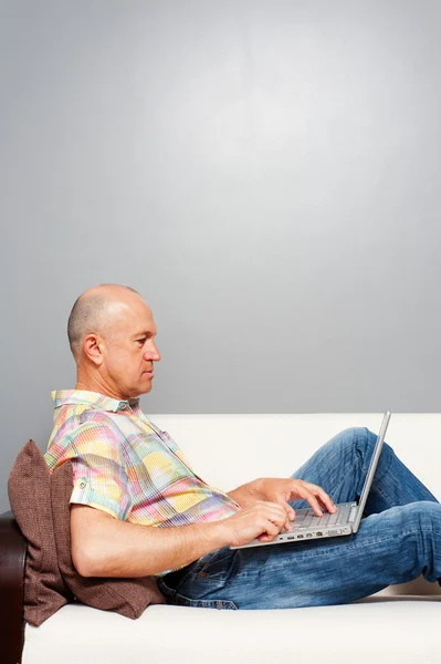 Homme âgé avec ordinateur portable sur le canapé — Photo