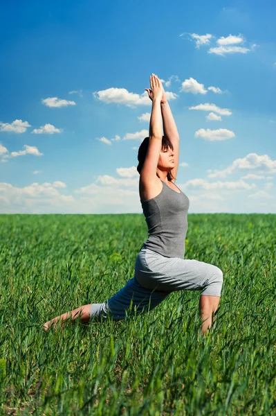 Yoga uygulamak ve sahada rahatlatıcı genç kadın — Stok fotoğraf
