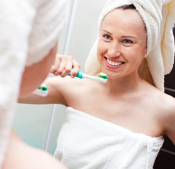 Женщина с зубной щеткой смотрит в зеркало — стоковое фото