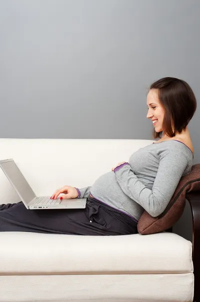 Mujer embarazada sonriente con portátil — Foto de Stock