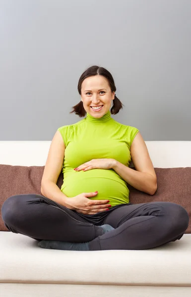 Buźka ciąży kobieta siedzi na kanapie — Zdjęcie stockowe