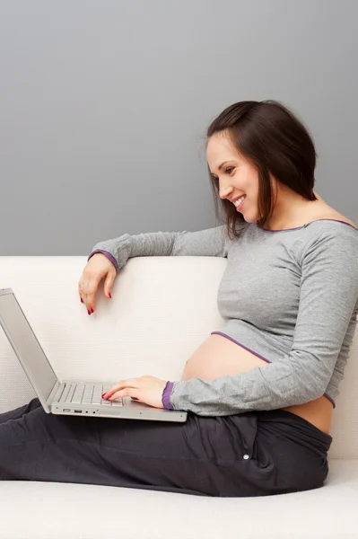 Беременная женщина расслабляется с ноутбуком — стоковое фото
