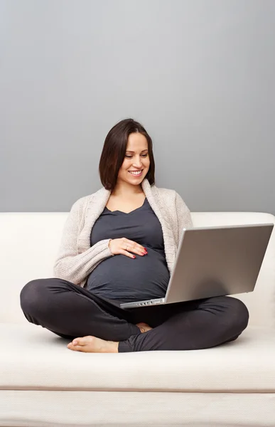Terhes nő ül a kanapén — Stock Fotó