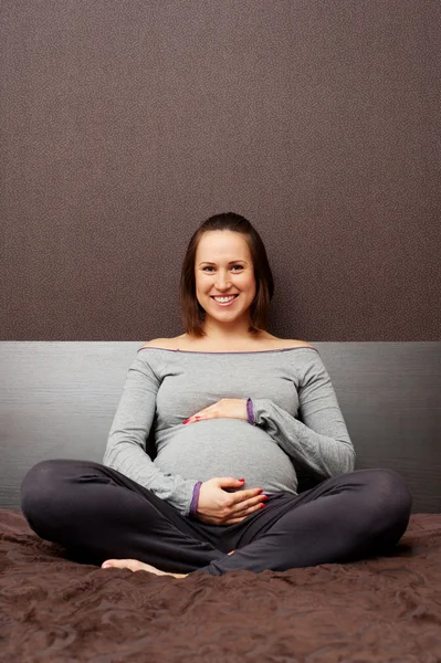 Gravid kvinna omfamnar hennes mage — Stockfoto