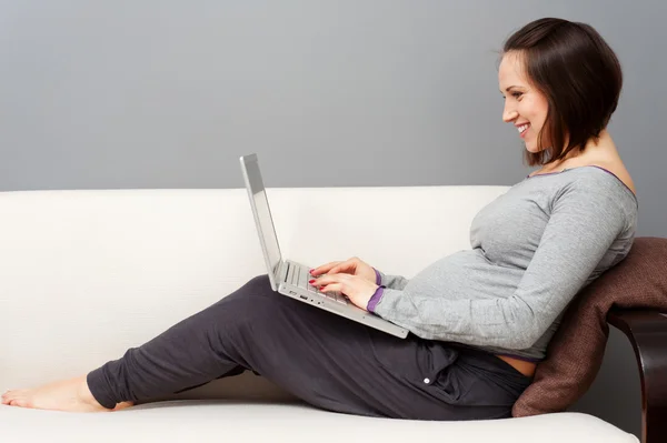 Femme enceinte gaie avec ordinateur portable — Photo