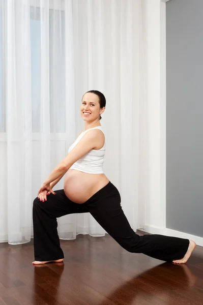 Mujer embarazada haciendo gimnasia de estiramiento — Stok fotoğraf