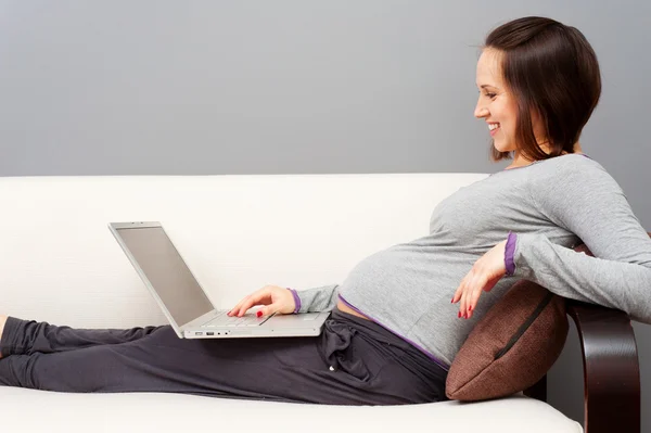 Улыбка беременной женщины с ноутбуком — стоковое фото