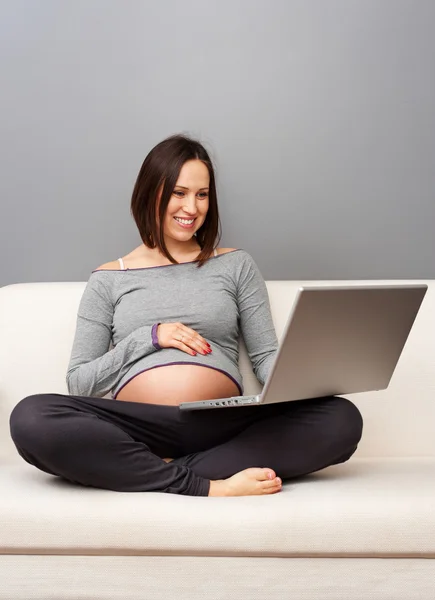 Беременная женщина смотрит на ноутбук — стоковое фото