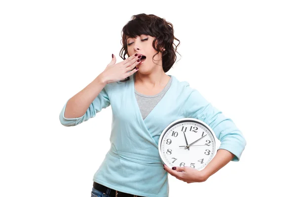 Молодая женщина держит часы и зевает — стоковое фото