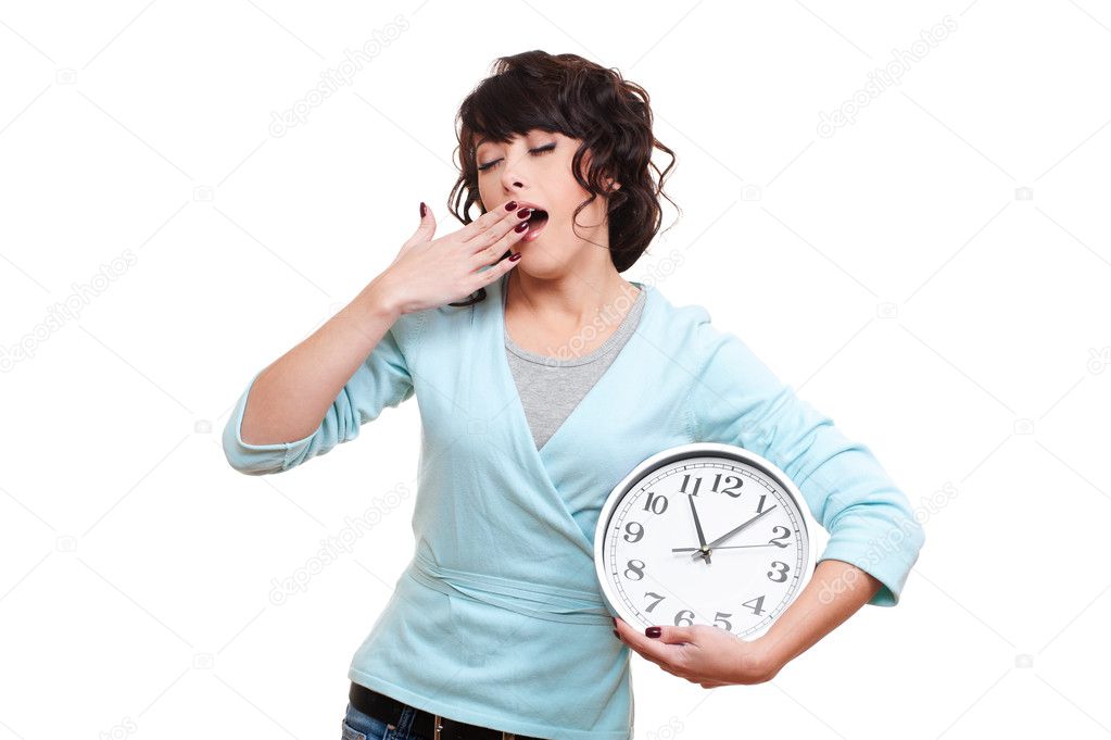 Young woman holding clock and yawning