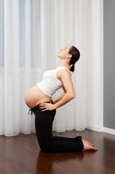 Gravid kvinna gör övning hemma — Stockfoto