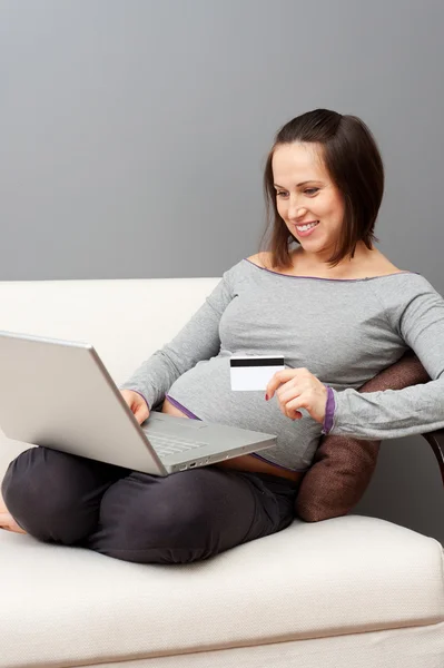 Těhotná žena drží notebook a kreditní karty — Stock fotografie