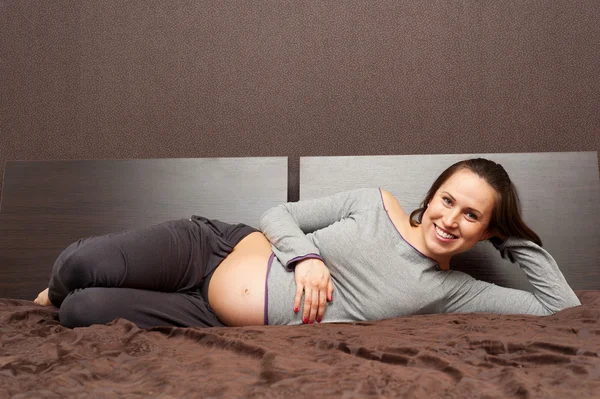 Mujer embarazada acostada en la cama y relajada — Foto de Stock