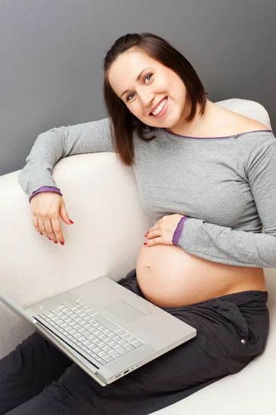 Улыбка беременной женщины с ноутбуком — стоковое фото