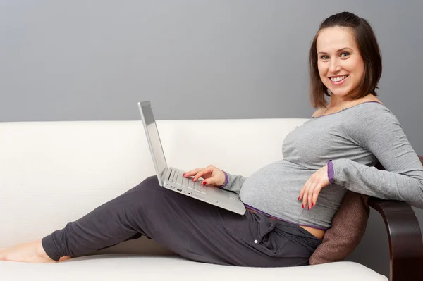 Mulher grávida com laptop em casa — Fotografia de Stock