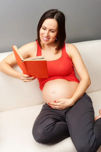 Gravid kvinna läser bok hemma — Stockfoto