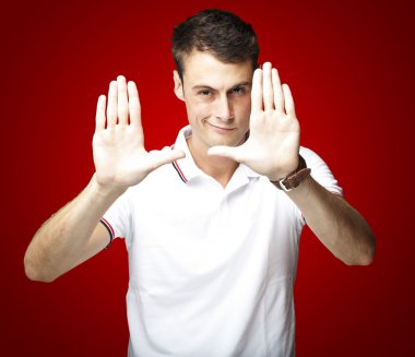 Portrait of young man doing photo gesture over red background clipart