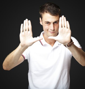 Portrait of young man doing photo gesture over black background clipart