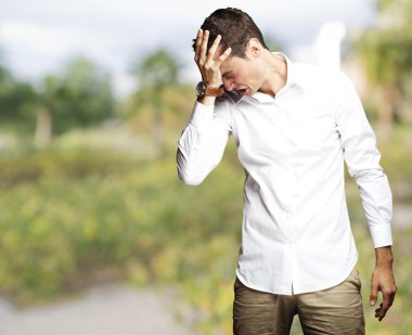 Angry young man doing frustration gesture at park clipart