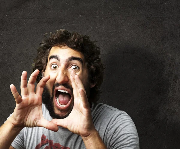 Porträtt av ung man skriker mot en grunge vägg — Stockfoto