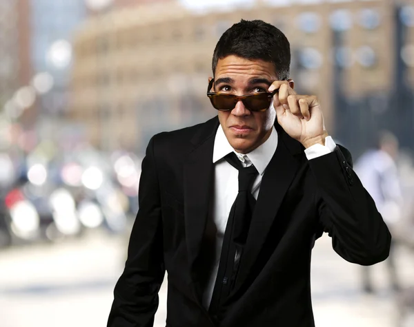 Portrait of business man taking off the sunglasses at crowded ci — Stock Photo, Image