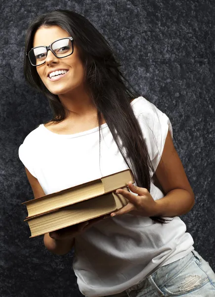 Retrato de una joven sosteniendo libros contra una pared grunge — Foto de Stock