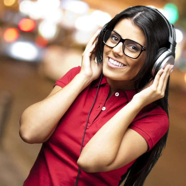 Hezká dívka posloucháte hudbu se sluchátky na ulici v blízko — Stock fotografie
