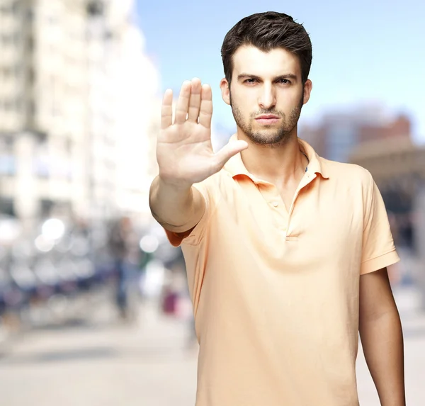 Ortrait of a comely young man doing Stop-Symbol an einer belebten Straße — Stockfoto