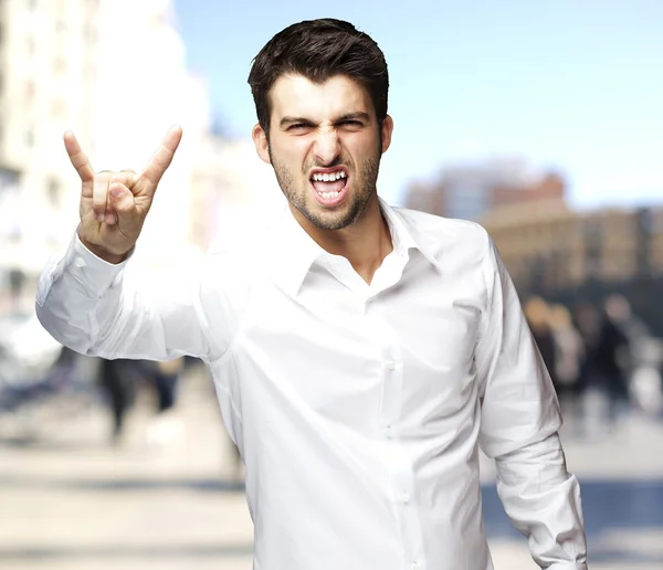 Portrait of young man doing rock symbol at city by night — Stock Photo, Image