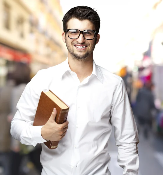 Retrato de un joven estudiante sosteniendo un libro en la ciudad —  Fotos de Stock