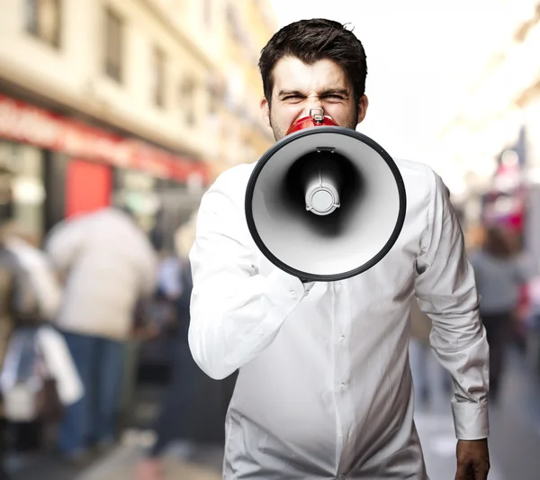 Portrait de jeune homme criant avec mégaphone en ville — Photo