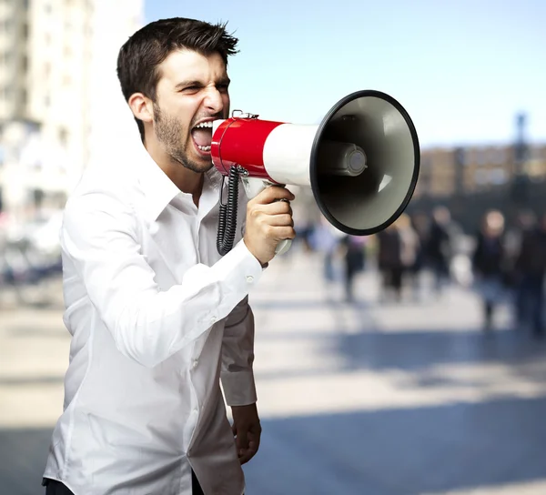 Retrato de un joven gritando con megáfono en la ciudad — Foto de Stock