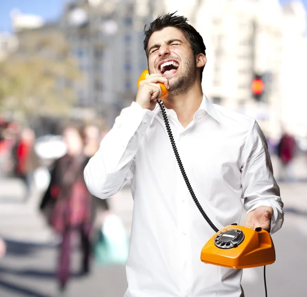 Porträt eines jungen Mannes, der auf der Straße mit einem alten Telefon telefoniert — Stockfoto