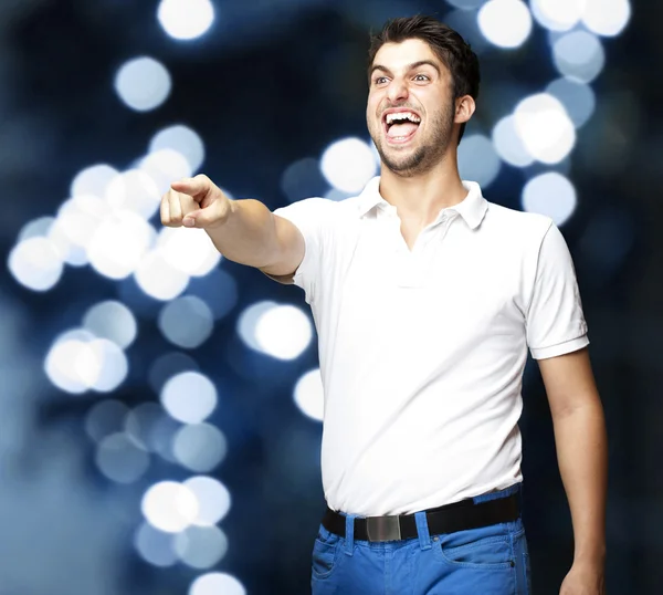 Retrato de un joven bromeando contra un fondo de luces azules —  Fotos de Stock