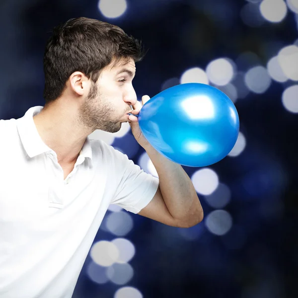 Портрет молодого чоловіка, який надуває блакитну кульку на блакитну брехню — стокове фото