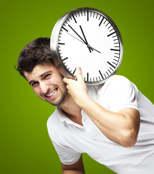 Portret przystojny młody mężczyzna prowadzenia zegar przeciwko gree — Zdjęcie stockowe