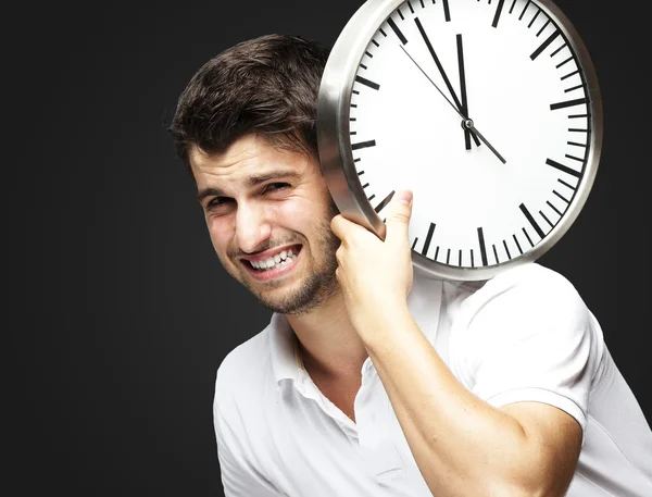 Portrait d'un beau jeune homme portant une horloge contre un blac — Photo