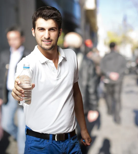 Portrait of young man offering water at a crowded street