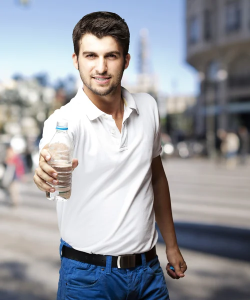 Retrato de jovem oferecendo água em uma rua lotada — Fotografia de Stock
