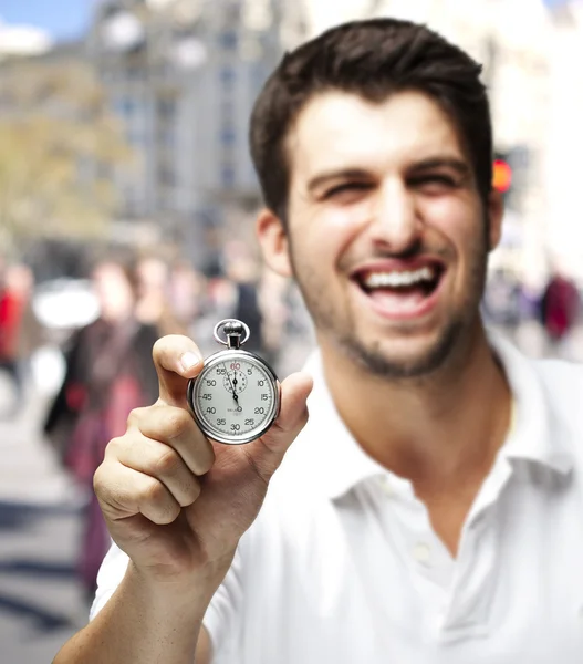 Πορτρέτο του νεαρού άνδρα, γελώντας και δείχνει ένα χρονόμετρο με διακόπτη, σε μια ευθεία γραμμή — Φωτογραφία Αρχείου