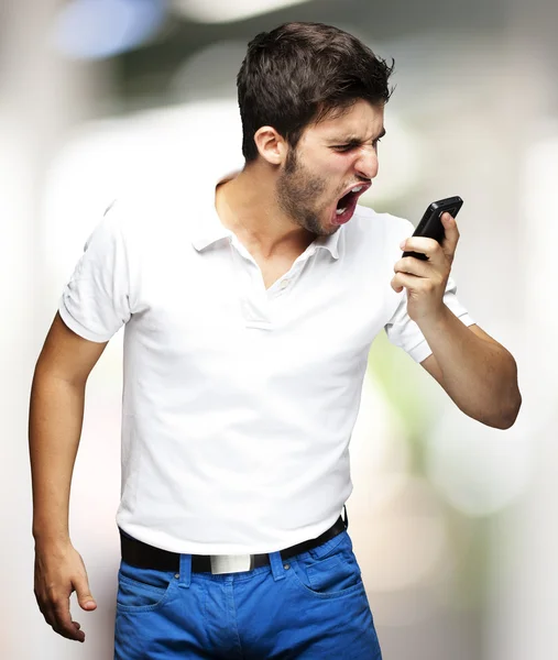Retrato de um jovem bravo gritando usando o interior móvel — Fotografia de Stock