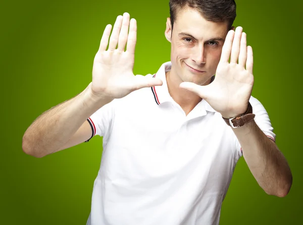 Портрет молодого человека, делающего фото жест на зеленом фоне — стоковое фото