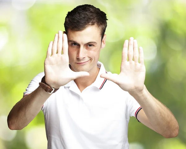 Portret van jonge man doen foto gebaar tegen een natuur-backg — Stockfoto