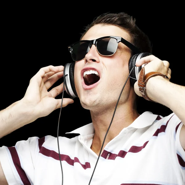 Portret van een knappe jongeman die luisteren naar muziek via zwarte b — Stockfoto