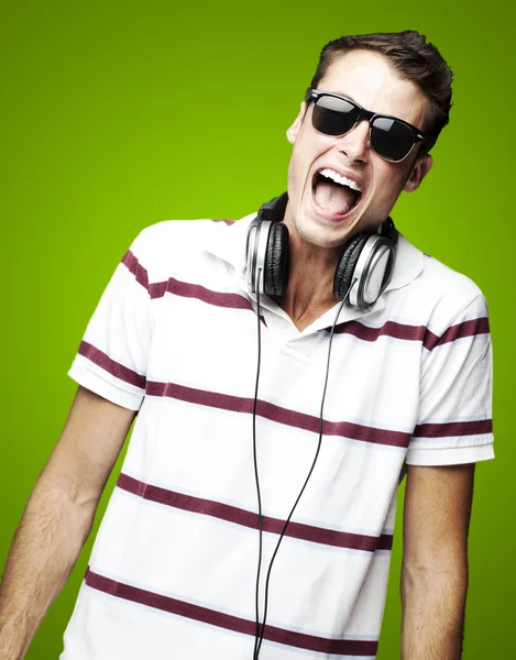 Retrato de un joven guapo escuchando música sobre verde b — Foto de Stock