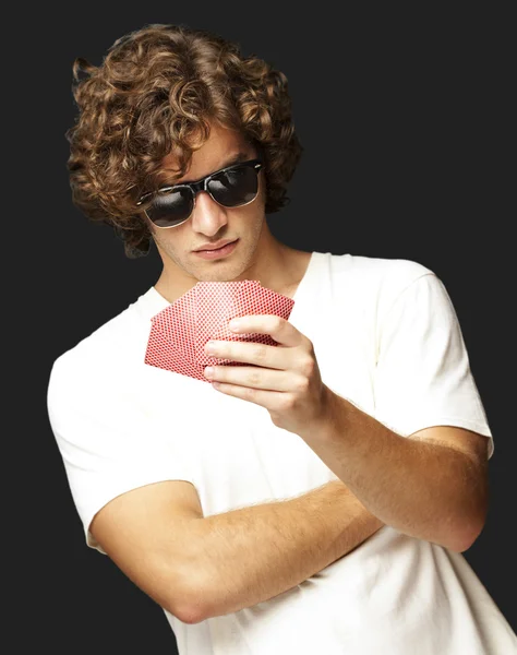 Portrait de jeune homme portant des lunettes de soleil et jouant au poker sur — Photo