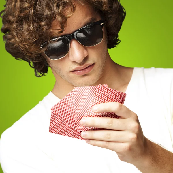 Portrét mladého muže, sluneční brýle a hrát poker nad — Stock fotografie